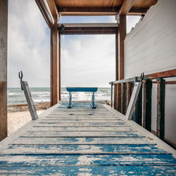 Empty chairs by swimming pool against sky