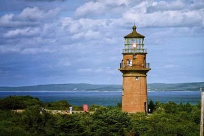 Lighthouse by sea against sky