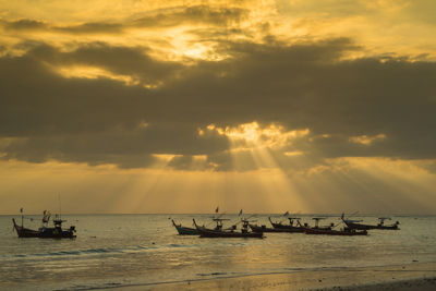 Silhouette boats sailing on sea against sky during sunset