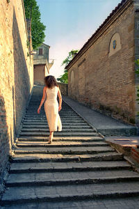 Rear view of woman walking on staircase against building