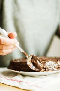 Midsection of person holding ice cream on table