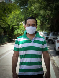 Portrait of young man standing outdoors wearing protective mask 