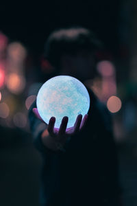 Close-up of hand holding illuminated lighting equipment at night