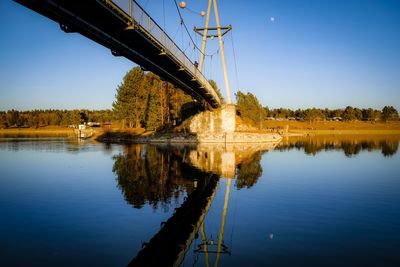 Low angle view of bridge over lake against clear blue sky