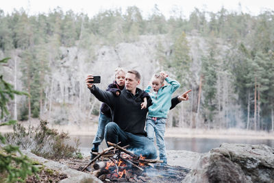 Father taking selfies with his kids whilst sitting next to a campfire