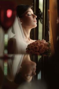 Close-up of young woman looking through window