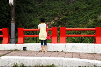 Rear view of man standing by railing against trees