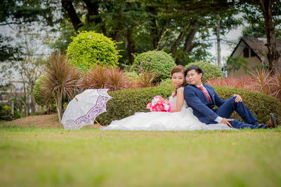 Smiling young bride and groom sitting in park