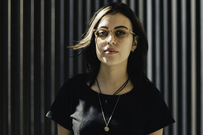 Portrait of young woman standing against wall