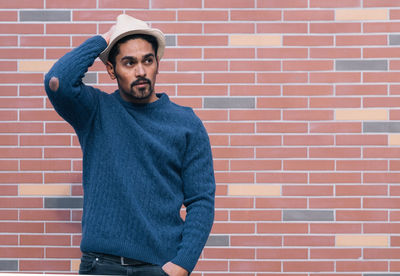 Portrait of man standing against brick wall