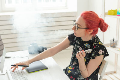 Young woman using phone while sitting on table