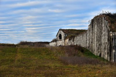 Abandoned built structure on field against sky