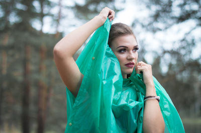 Young woman looking away while wearing raincoat in forest