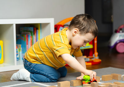 Toddler boy with a bandage or cast on his leg plays with toys and blocks. 
