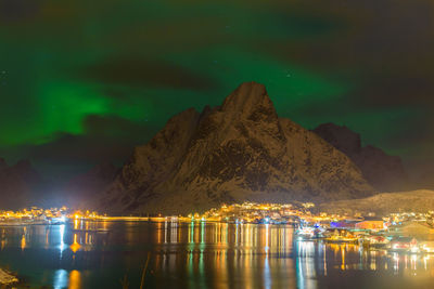 Scenic view of lake by illuminated mountain against sky at night