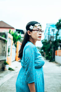 Young woman looking away while standing against built structure