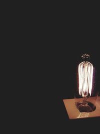 Close-up of illuminated lamp over black background