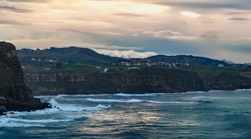 Scenic view of sea and mountains against sky