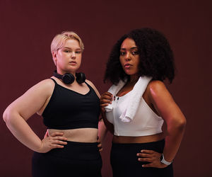 Portrait of females standing against colored background