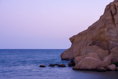 Rock formation in sea against clear sky