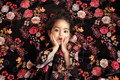 Portrait of cute girl against floral curtain