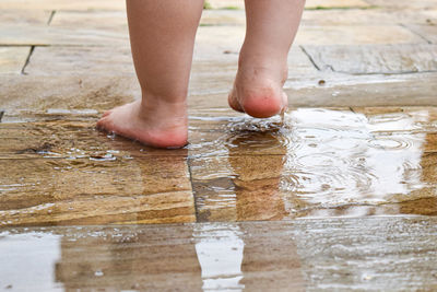 Low section of child standing on wet shore
