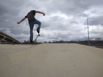 Full length of man skateboarding on street against sky