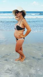 Pregnant woman standing at beach 