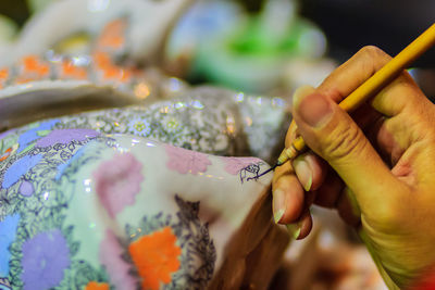 Cropped image of artist painting on ceramics