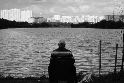 Rear view of man looking at river in city