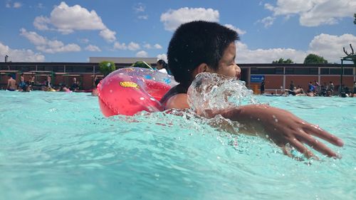 Girl playing in swimming pool against sky