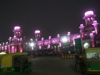 Illuminated city street against sky at night