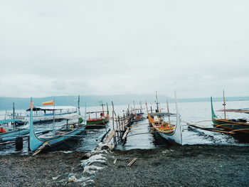 Boats moored at harbor against sky