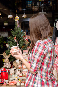 Woman choosing christmas gifts at small craft pottery store. wintertime holidays mood in tropic