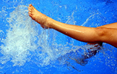 Low section of child splashing in swimming pool