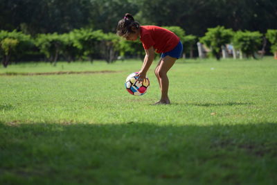 Girl playing with ball at park on sunny day