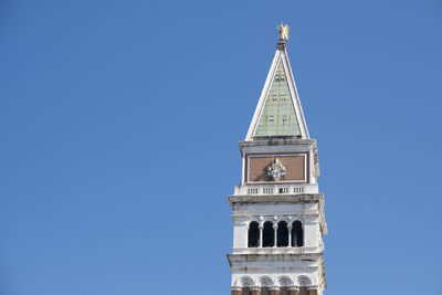 Low angle view of bell tower against blue sky