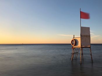 Lifeguard hut on sea against sky during sunset