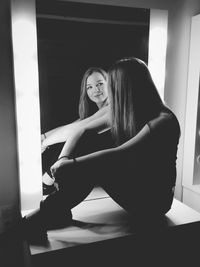 Woman sitting on table reflecting in mirror