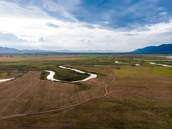 Scenic view of road amidst field against sky