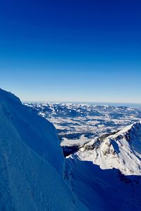 Scenic view of snowcapped mountains against clear blue sky