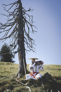 Woman sitting on field against clear sky