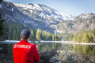 Rear view of man standing on snowcapped mountain