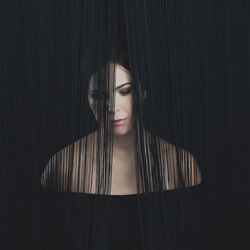 Close-up portrait of young woman against black background