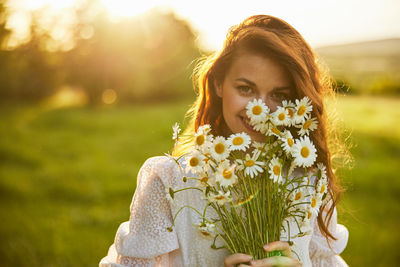 Portrait of young woman standing against plants