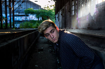 Thoughtful teenage boy standing in abandoned railroad station