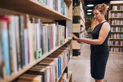 Woman reading book in public library. reading and learning. searching for literature. university