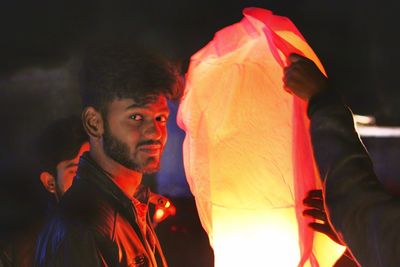 Portrait of young man holding camera at night