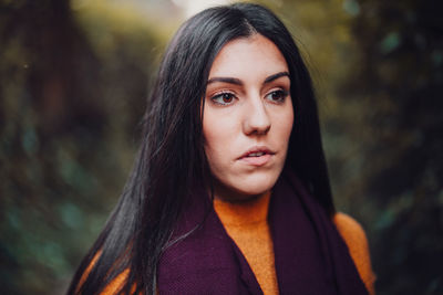 Close-up of young woman looking away while standing in forest during winter