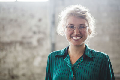 Portrait of smiling blond female programmer standing at creative office